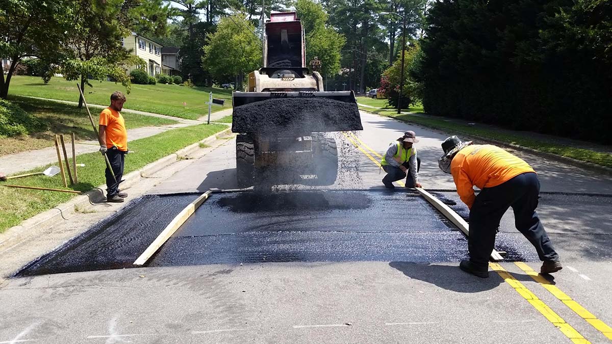 Crew patching a road with asphalt